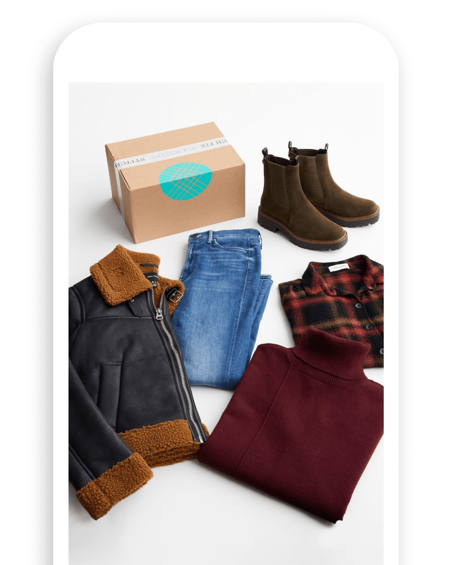 [3.] Phone with image of Stitch Fix box and selection of fall clothing including shearling bomber jacket, flannel shirt, blue jeans, brown chelsea boots and burgundy turtleneck sweater
